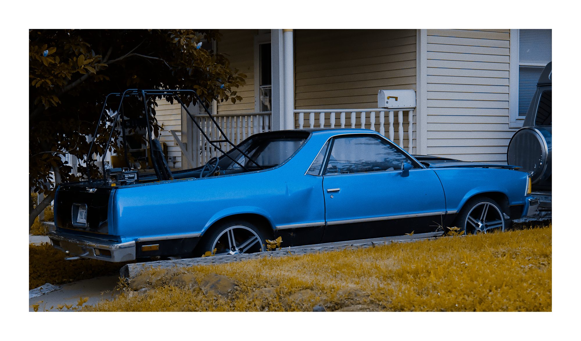 A blue car parked beside a house.