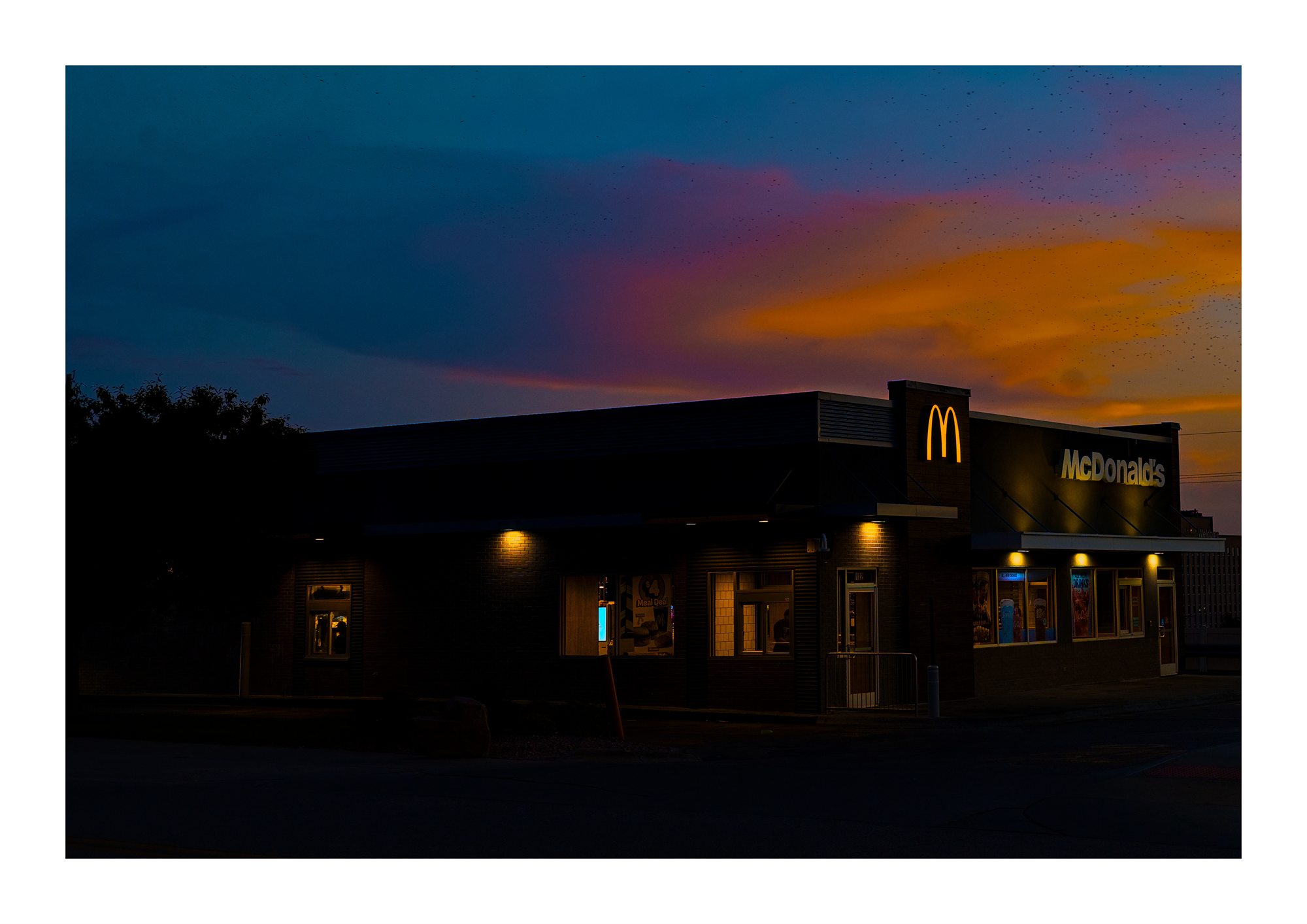 A McDonald's building at dusk under a colorful sky.