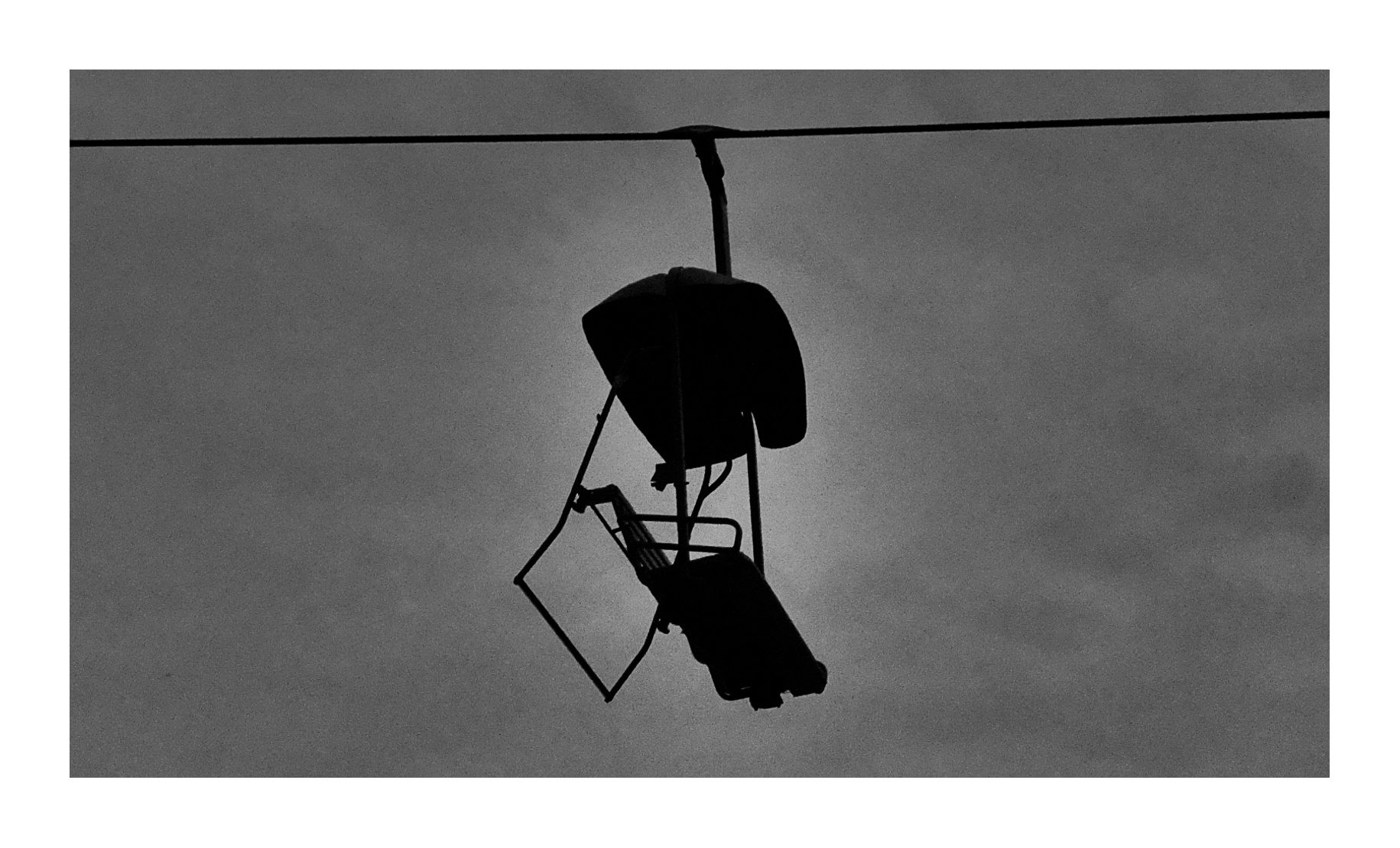 Black and white photograph of a hanging streetlight or fixture.
