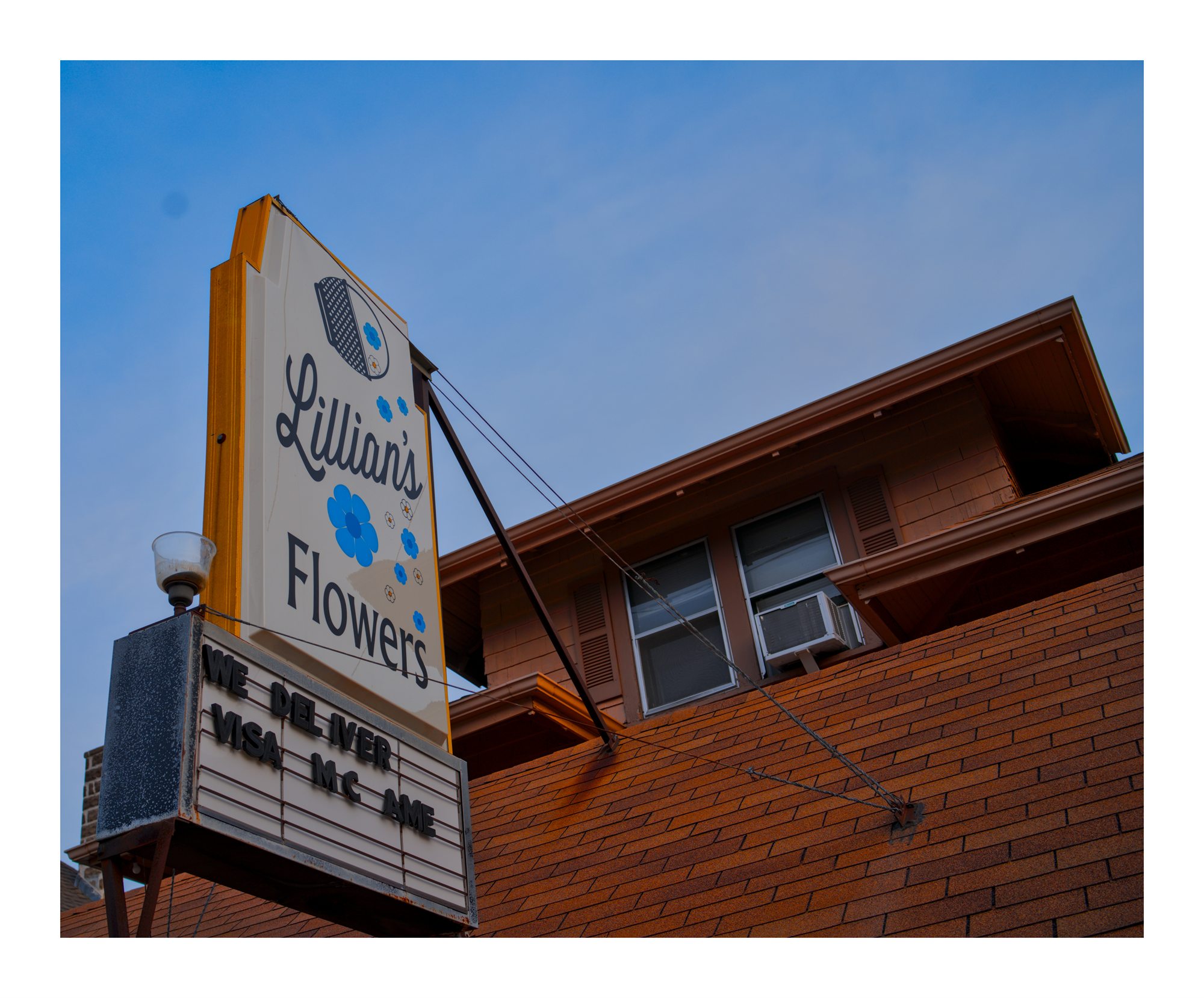 A sign for Lillies Flowers on a brick building.