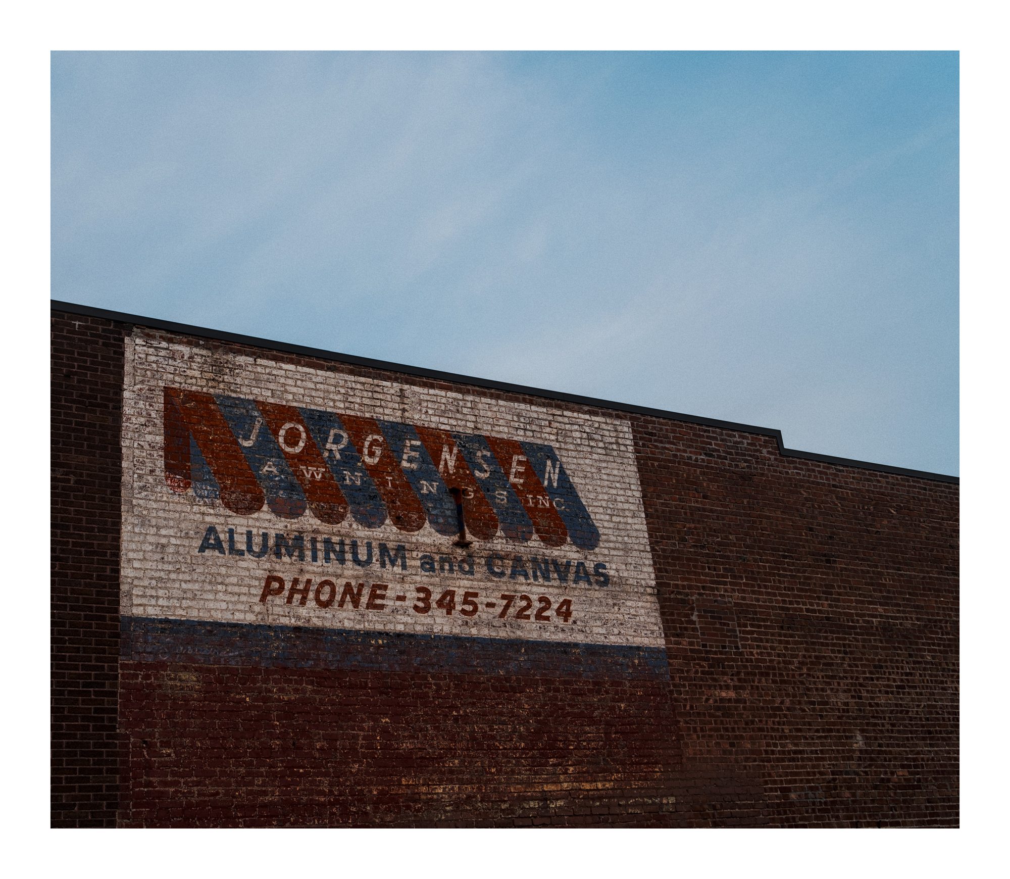 A faded Nordsen aluminum sign on a brick wall.