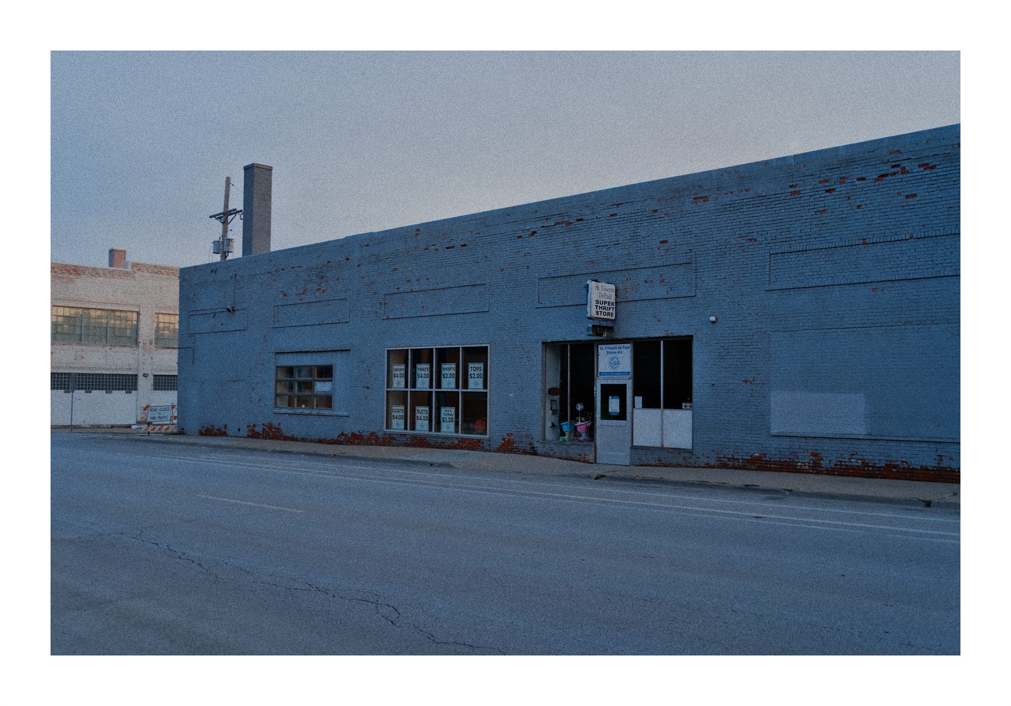 A pale blue industrial building on a quiet street.