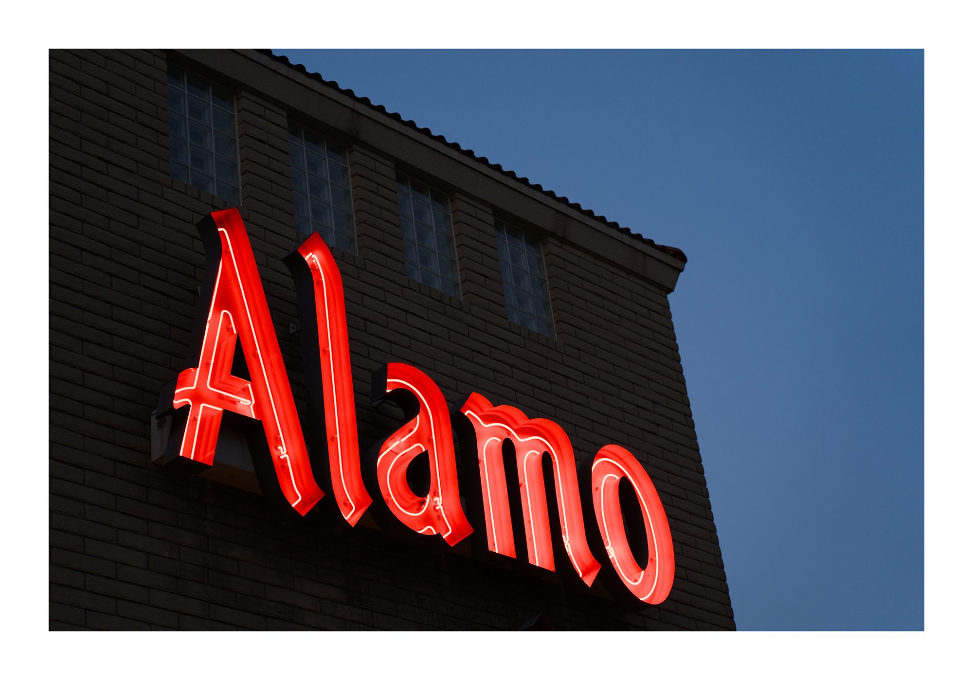 A red Alamo sign on a brick building.