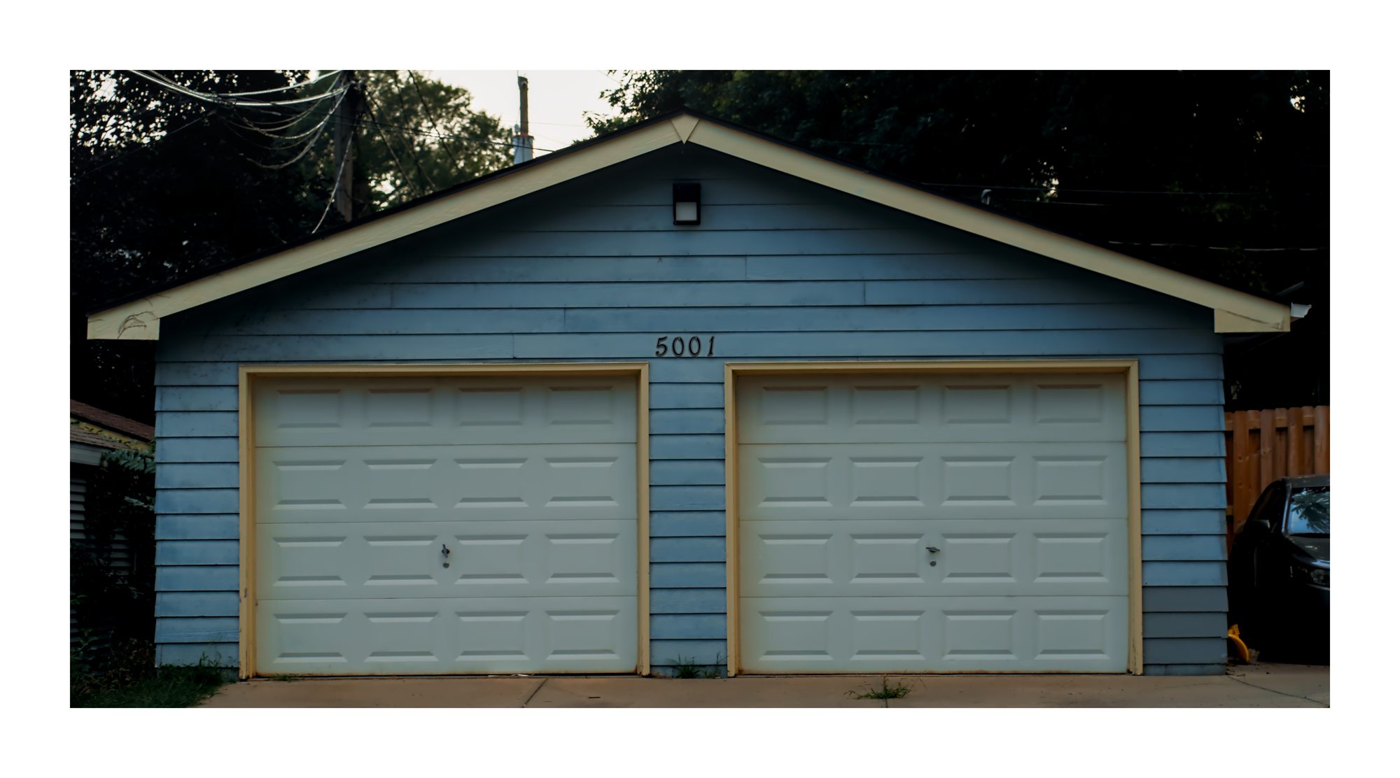 A small blue garage with two white doors.