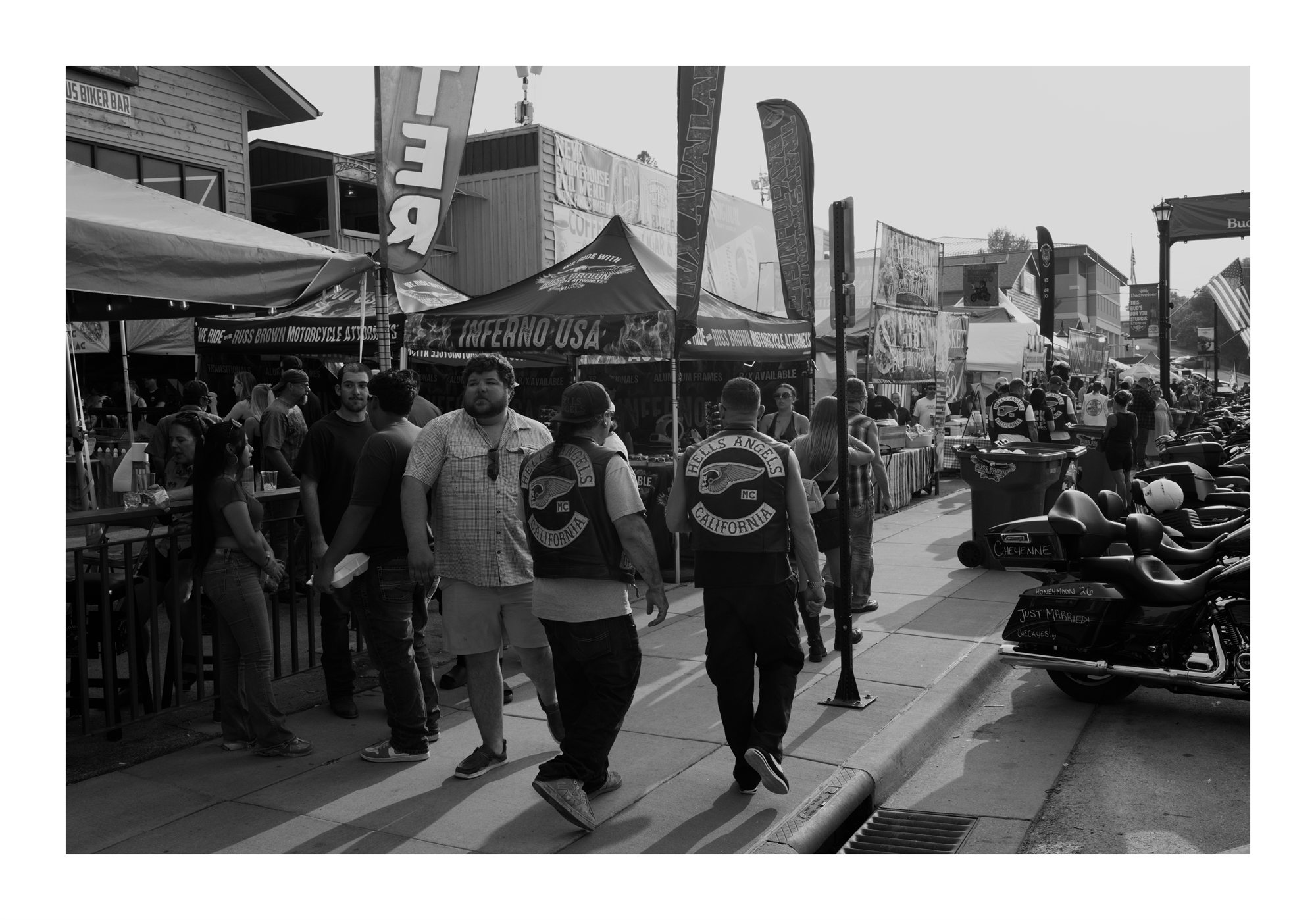 Crowds and motorcycles along a Sturgis street in black and white.